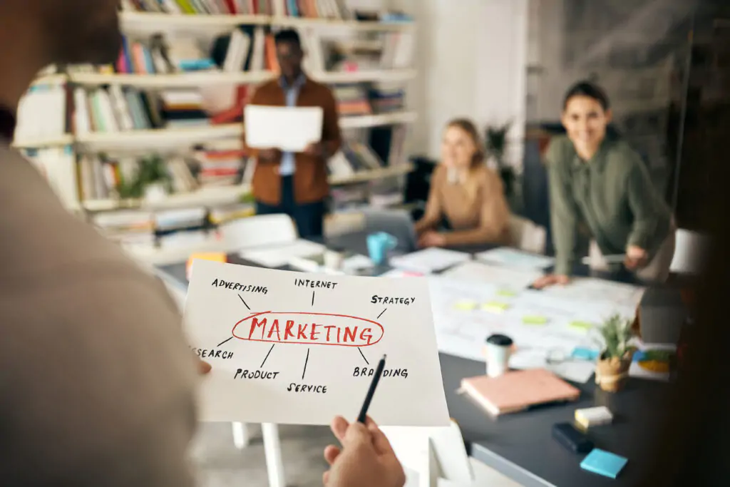 Reunión de equipo en una agencia de marketing en Querétaro, discutiendo estrategias de branding, SEO y diseño web con un esquema de marketing en papel