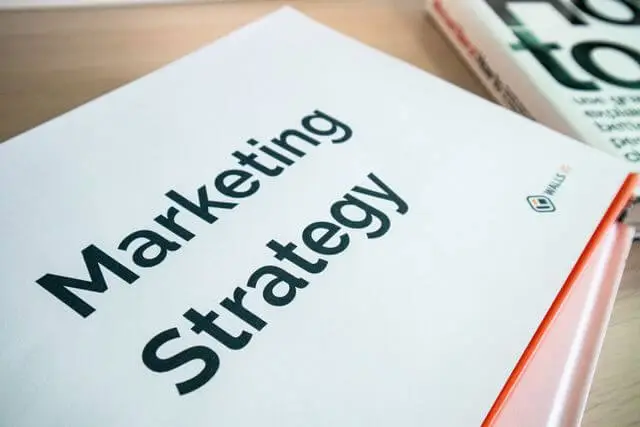 Libreta con la portada "Marketing Strategy" sobre un escritorio de madera, representando la planeación de estrategia de marca