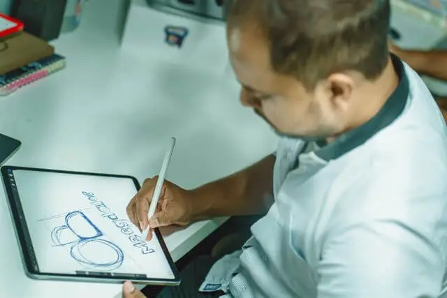 Diseñador dibujando un boceto de logo en una tablet con lápiz digital