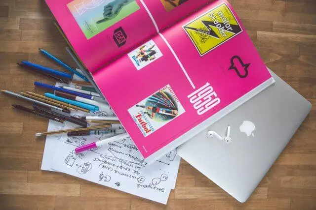 Lápices, bocetos y un libro de diseño con logotipos vintage sobre un escritorio de madera